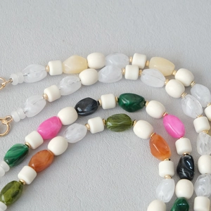 Gros plan d'une chaîne de perles en résine acrylique colorée avec des maillons dorés