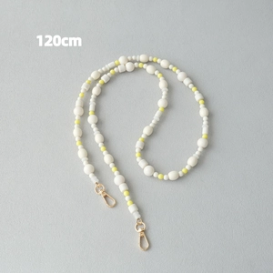 Vue détaillée d'une chaîne en perles de résine jaune et blanche de 120 cm avec fermoir or