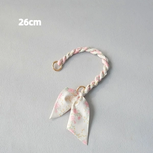 Close-up of a 26cm floral fabric woven handbag strap with golden rings and a matching bow