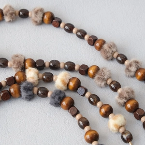 Macro detail of wooden bead strap with colorful mini faux fur pom-poms for bags