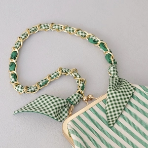 Détail d'un sac vintage en toile rayée verte avec bandoulière chaîne et ruban de soie