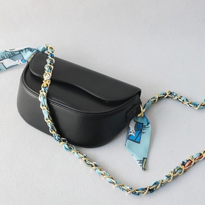 Black half-moon saddle bag featuring a light blue cartoon silk scarf interwoven chain strap