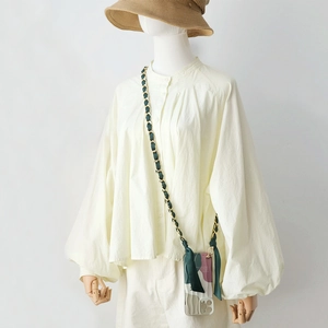 Detail of crossbody phone case with gold metal chain and dark green ribbon strap