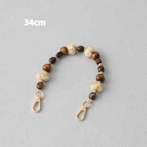 Detail view of 34cm fashion strap with dark wood beads and soft beige faux fur pom poms