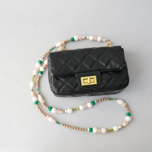 Détail d'un sac bandoulière matelassé noir avec sangle en perles acryliques multicolores
