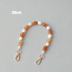 Détail de la chaîne de 38cm en perles de résine marbrée orange et fermoir doré