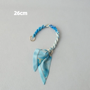 Detail view of 26cm silk scarf bag strap with golden clasp and blue gradient bow