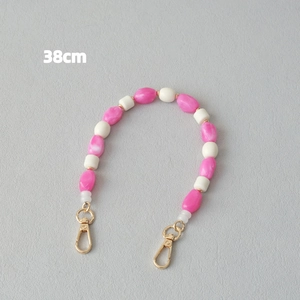 Détail d'une chaîne de 38 cm en perles acryliques roses et blanches avec fermoirs dorés