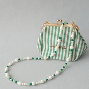 Détail d'un sac vintage rayé avec bandoulière en perles acryliques colorées et élégantes