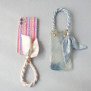 Detail of silk scarf handles and wave-edge phone cases with floral patterns and gold rings