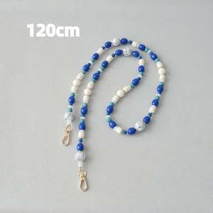 Détail d'une chaîne perlée de 120cm avec perles bleues et blanches et fermoirs dorés