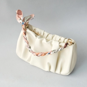 Close-up of beige cloud pouch with silk scarf woven handle and gold hardware