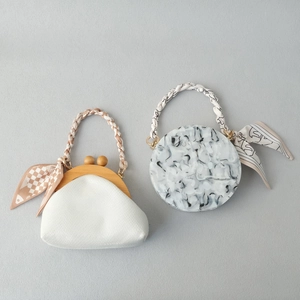 Detail of luxury silk scarf handle on cloud clutch and marble effect hard shell handbag