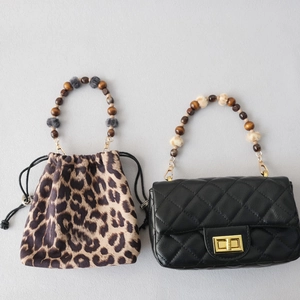 Detail of wooden beads and plush pompom shoulder straps on fashion handbags
