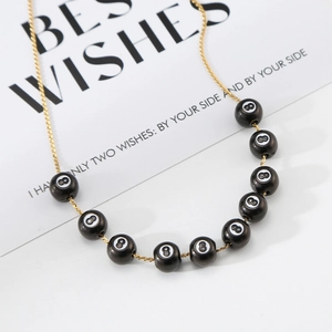 Collar de cadena dorada con cuentas negras de bola 8 sobre una elegante tarjeta de regalo