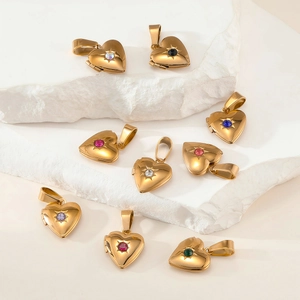 Macro detail of gold-plated heart lockets with colorful birthstone zircons on stone