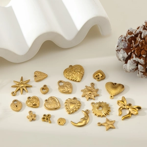 Detailed view of 18K gold plated stainless steel heart and bow pendants on white stone