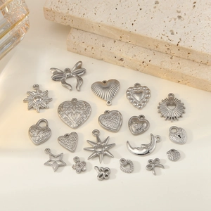 Silver stainless steel charms collection with heart and bow motifs on stone background