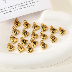 Gros plan de pendentifs lettres en forme de cœur dorés dans un plateau blanc pour colliers