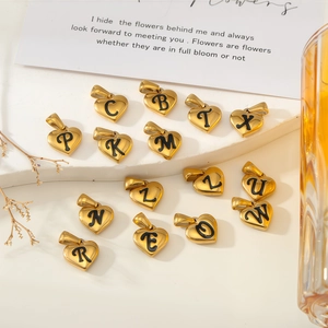 Pendentifs cœur dorés avec lettres en émail noir sur un support en pierre blanche