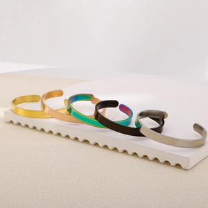 Detail of five stackable open C-shaped stainless steel bracelets in various metallic finishes
