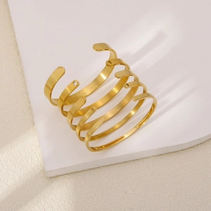 Polished gold multi-layer spiral cuff bracelet set on a modern white minimalist display