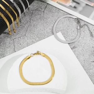 Detailed macro view of gold and silver flat snake bone bracelets with lobster clasp and chain