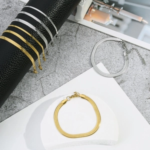 Detailed view of flat snake bone chain bracelets in gold and silver with lobster clasps
