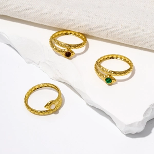 Close-up of golden snake rings with malachite and scale texture on fabric base