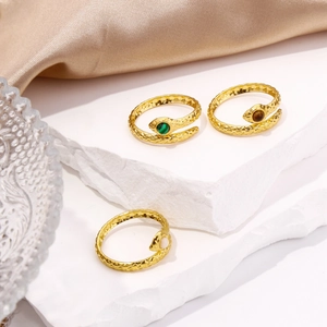 Macro detail of snake-shaped rings with green and brown gemstones on white rock