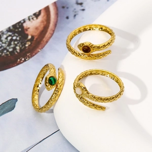 Macro detail of three gold snake rings with green and white stone inlays and scales