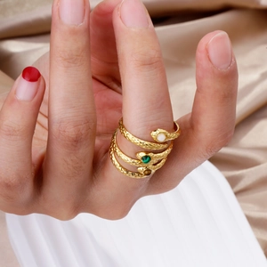 Detailed close-up of golden snake spiral rings with malachite eyes on silk background