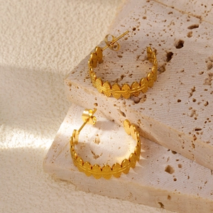 Macro view of gold-plated leaf texture on C-shaped earrings over natural stone