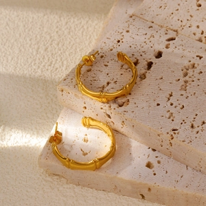 Dettaglio di orecchini a cerchio in bambù placcati oro 18k su superficie in pietra