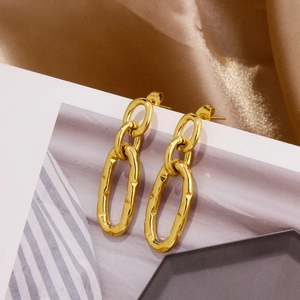 Detail of gold U-shaped double hoop earrings with lava texture on white magazine background
