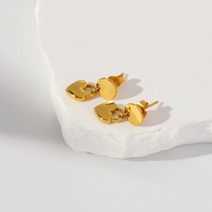 Vue détaillée de boucles d'oreilles cœur en or 18k sur un bloc de marbre blanc