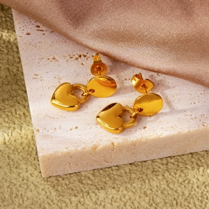 Boucles d'oreilles pendantes cœur en or 18k sur fond minimaliste en travertin