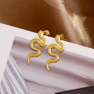 Macro shot of 18k gold snake stud earrings showing detailed scale texture on silk