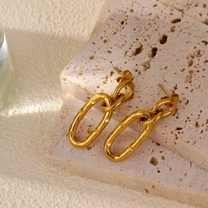 Detail of gold U-shaped earrings with diamond-cut texture on beige travertine stone