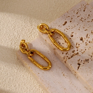 Detail of gold U-shaped double-hoop earrings with hammered lava texture on stone base