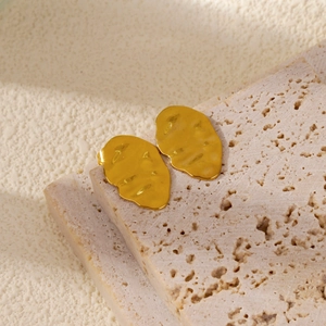Detailed view of gold irregular lava texture leaf earrings on beige stone display base