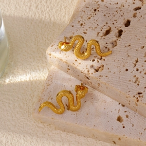 Macro shot of gold-plated snake stud earrings with textured hammer finish on stone