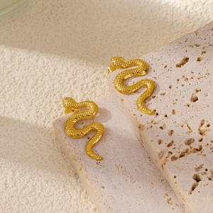 Macro shot of gold snake stud earrings showing detailed scale texture on stone base