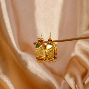 Detail of gold geometric triangle earrings featuring smooth and hammered textures on silk
