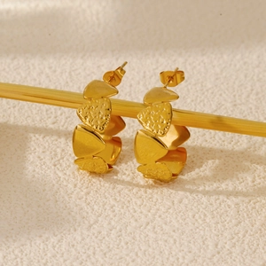 Macro shot of gold layered hoop earrings with textured hammered finish on a stand