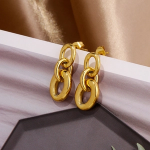 Close-up of golden interlocking triple-link dangle earrings on a textured silk background