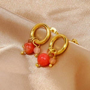 Dettaglio di orecchini in oro 18k con pendente in agata rossa su seta color champagne