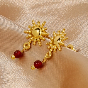 Eleganti orecchini a girasole dorati con pendenti in rubino rosso su seta champagne