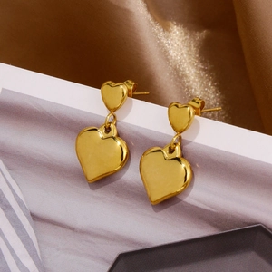 Détail de boucles d'oreilles pendantes en forme de cœur doré avec finition miroir polie