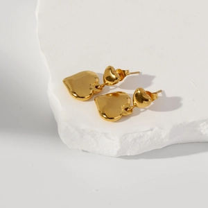 Vue détaillée de boucles d'oreilles doubles cœurs dorés avec finition miroir sur pierre